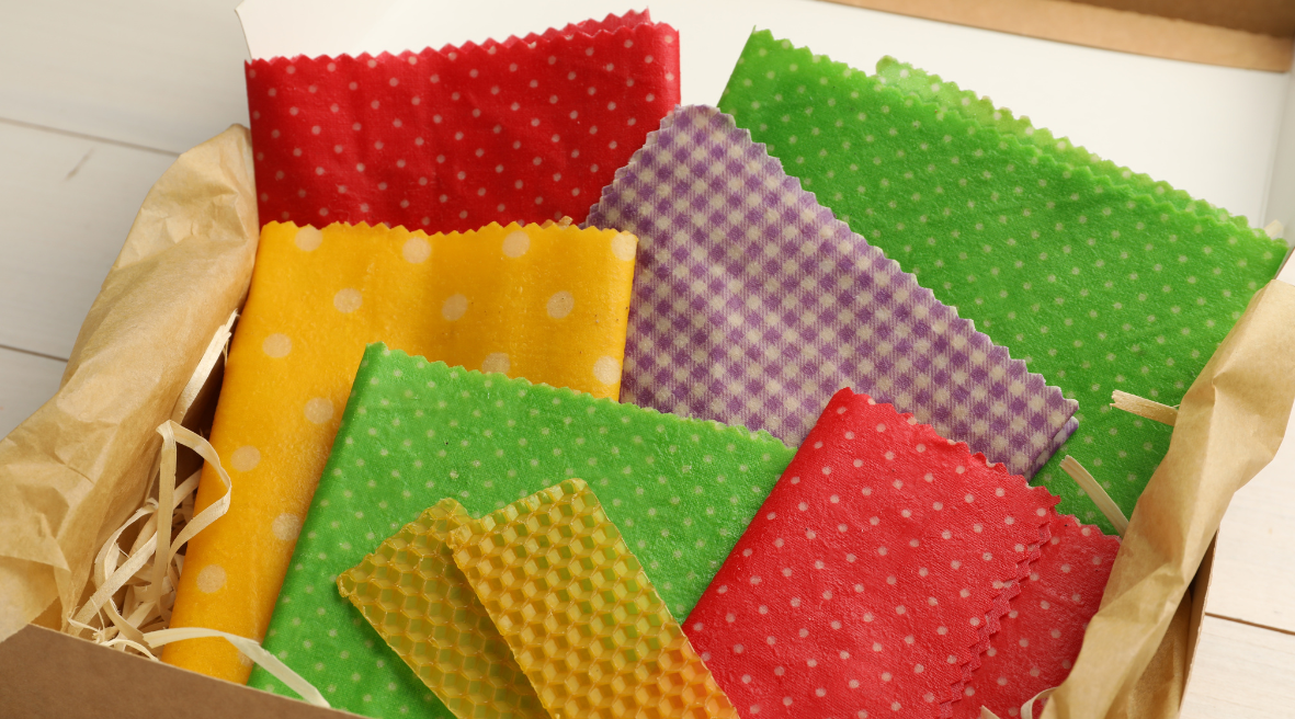 Emballages réutilisables en cire d'abeille de différentes couleurs et motifs dans une boîte en carton.